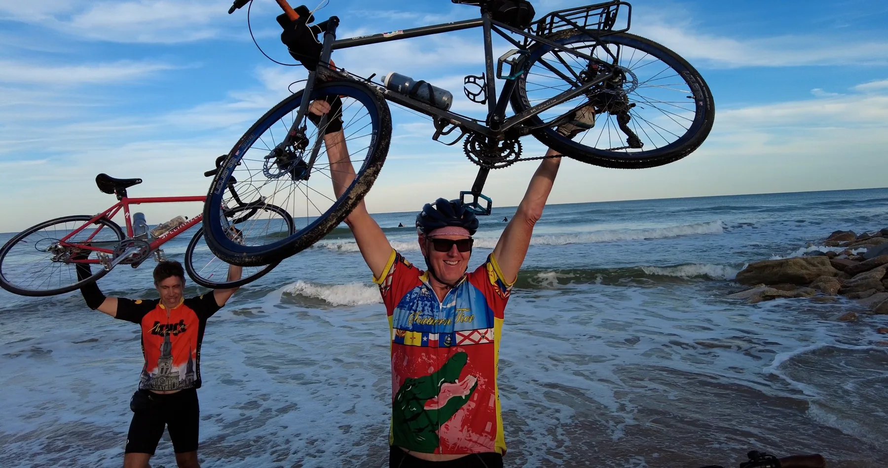 Cyclists lifting bicycles at the ocean